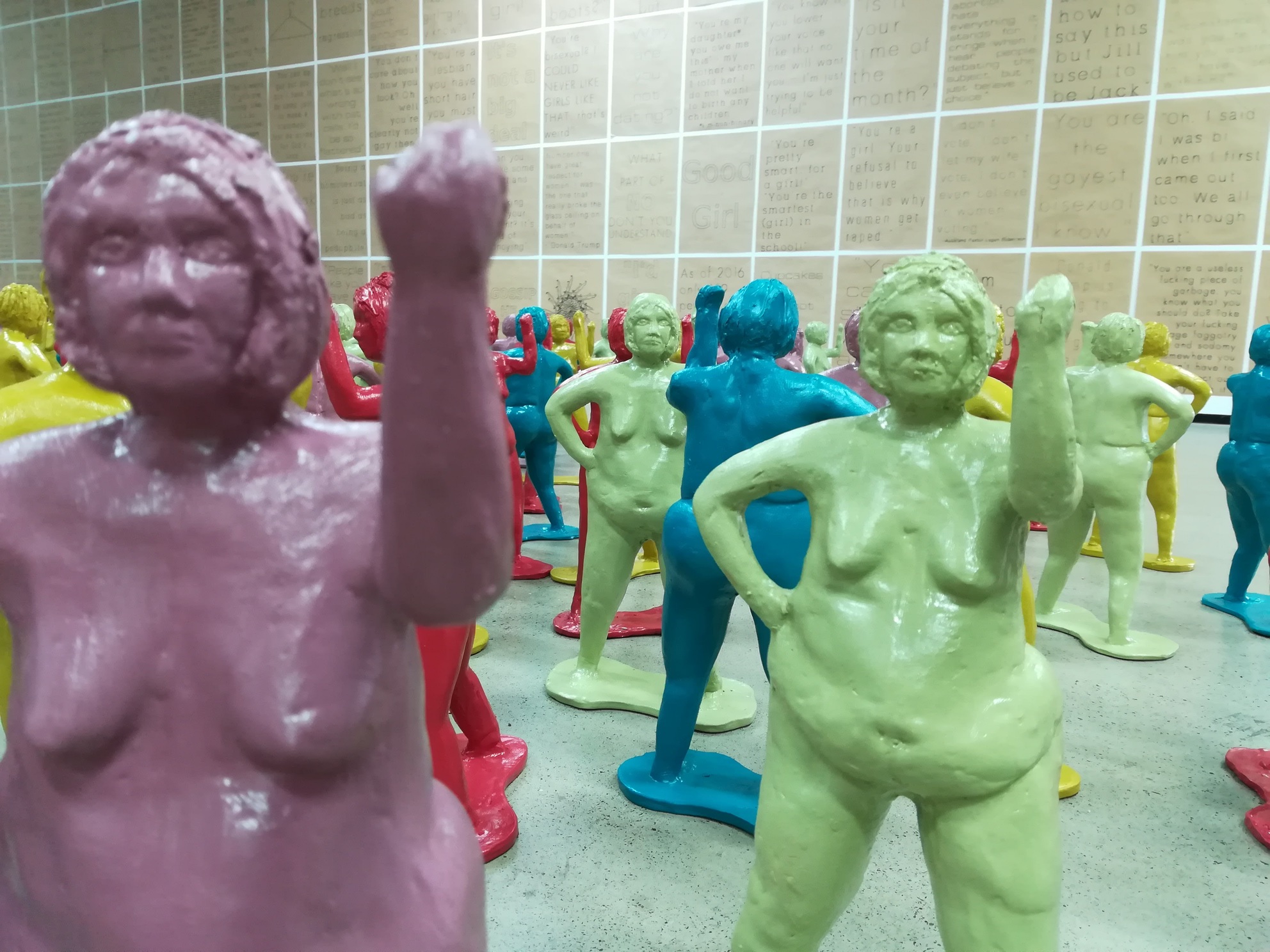 Close up photo of ceramic Bertha figures with feminist posters in background