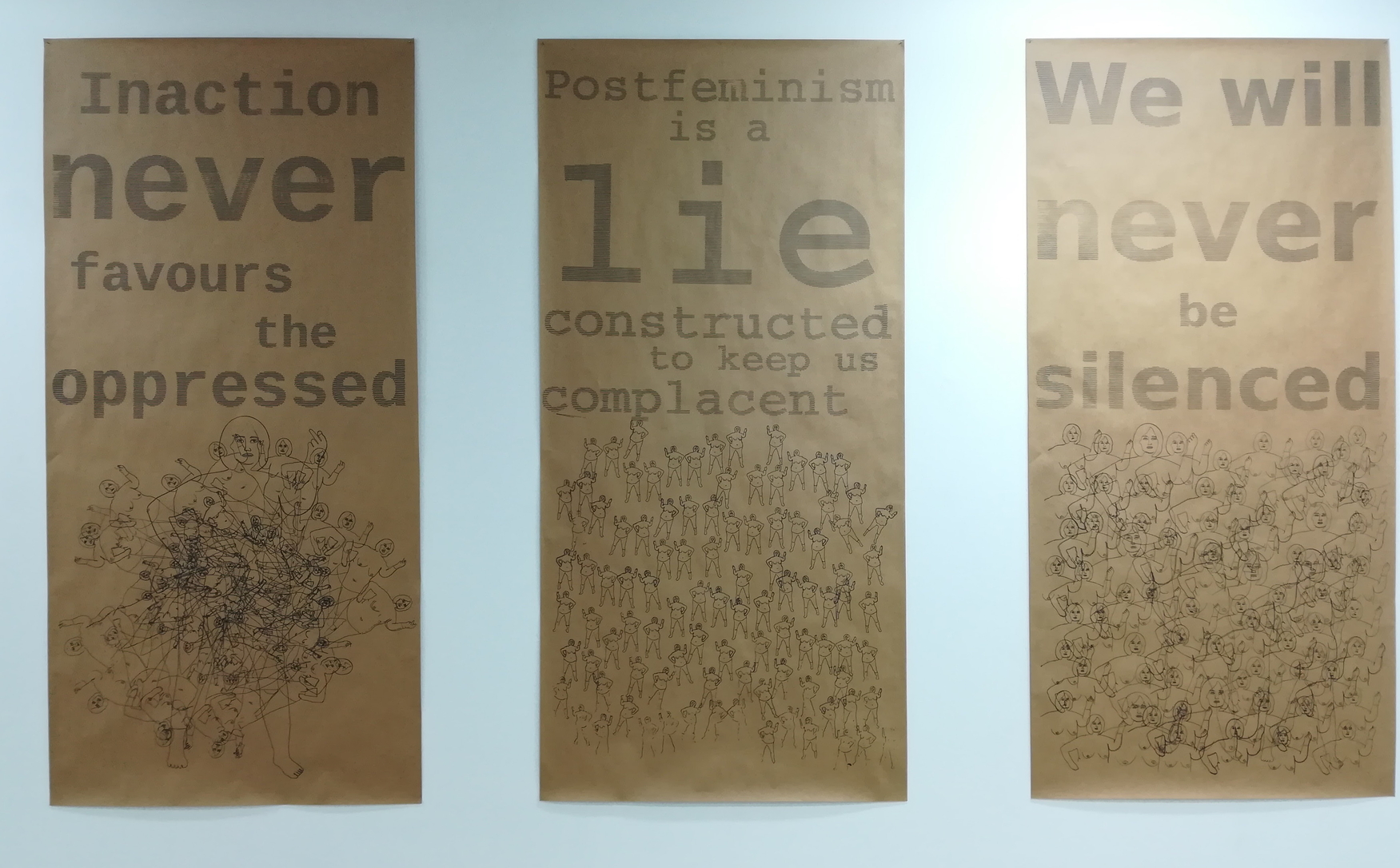 Photos of three 2m high posters that read "Inaction never favours the oppressed", "Postfeminism is a lie constructed to keep us complacent", "We will never be silenced"